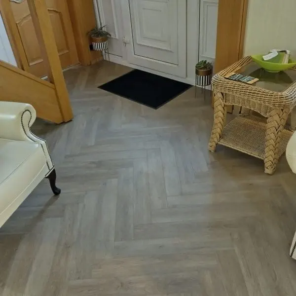 A spacious, well-lit room showcasing Pro-Tek Flooring, with a sleek surface and subtle texture. The setting features modern furniture, emphasizing the flooring’s contemporary appeal and durability.